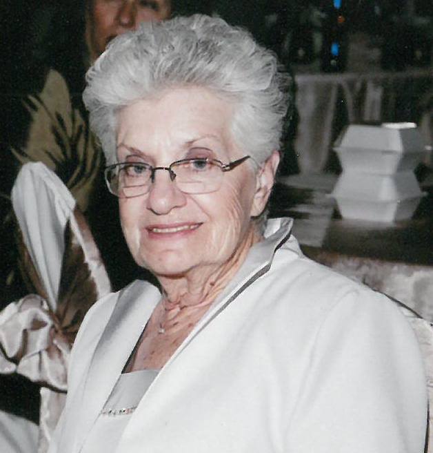 An older woman in glasses sitting at a table.