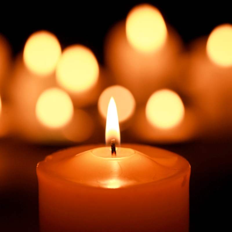 A group of candles lit in front of a dark background.