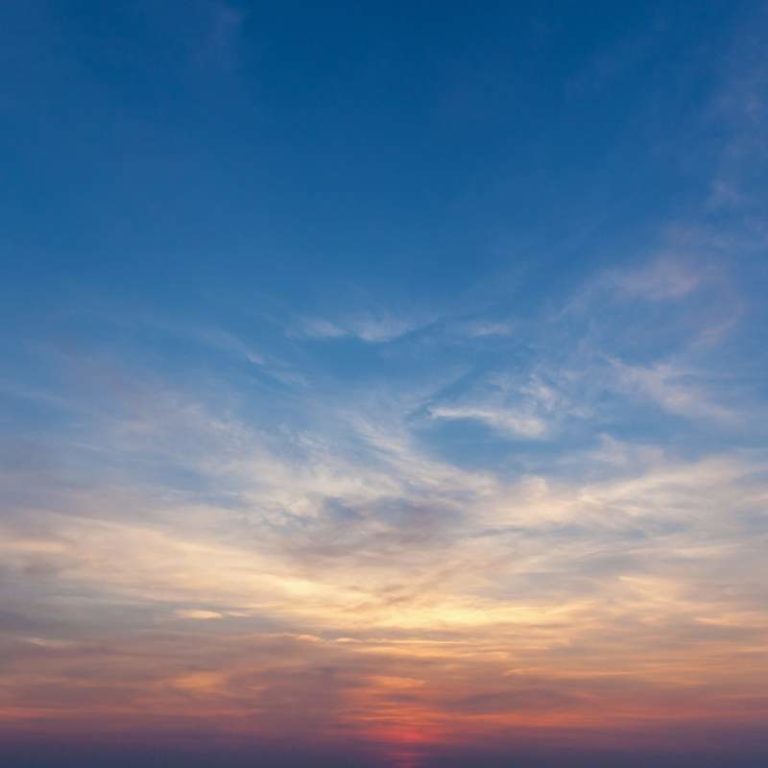 A sunset over the ocean with a boat in the background.