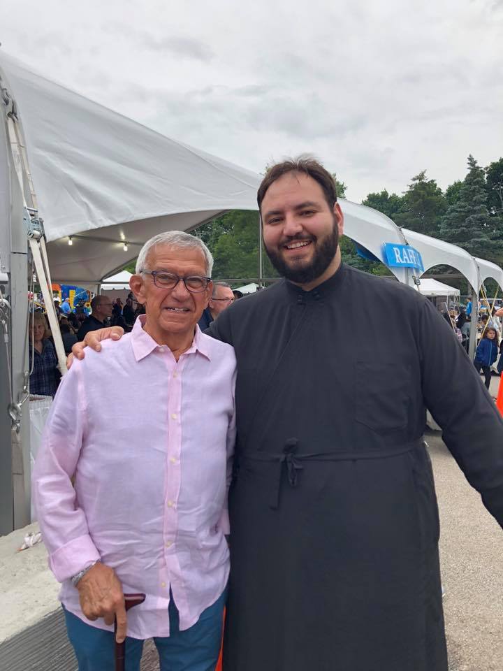 Two men standing next to each other in front of a tent.