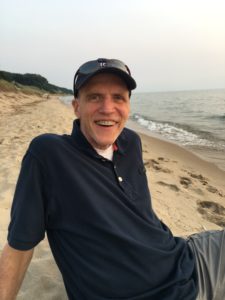 A man sitting on a beach with a smile on his face.