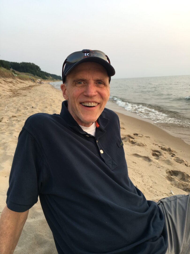 A man sitting on a beach with a smile on his face.