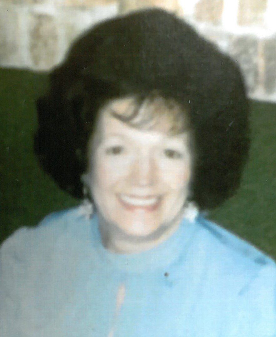A woman in a blue shirt smiles for the camera.
