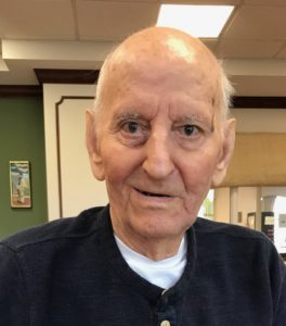 An older man in a blue shirt sitting at a table.