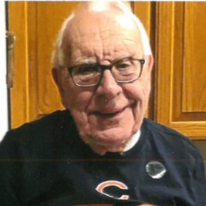 An older man with glasses is holding a football.
