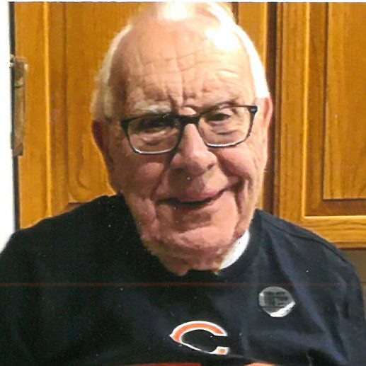 An older man with glasses is holding a football.