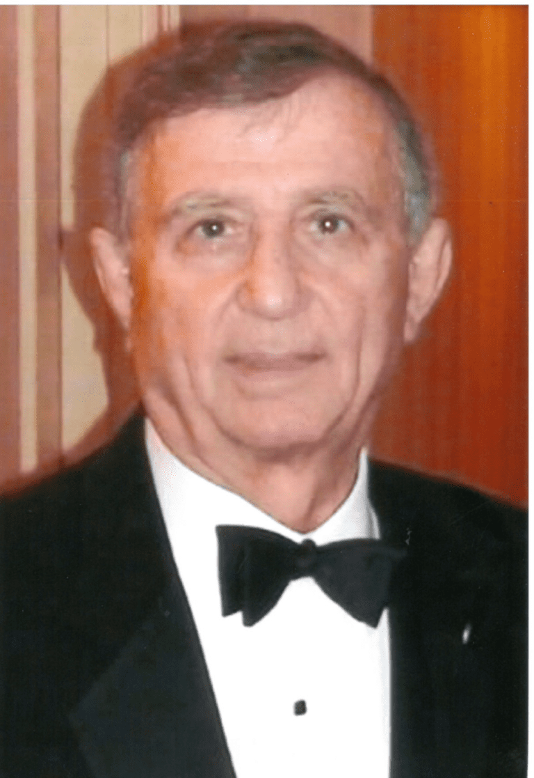An older man in a tuxedo posing for a photo.