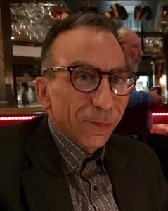 A man in glasses sitting at a bar.