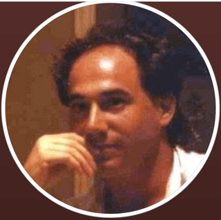 An image of a man with his hand on his chin.