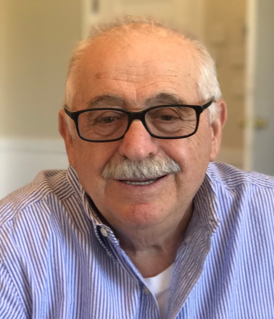 An older man wearing glasses and a mustache.