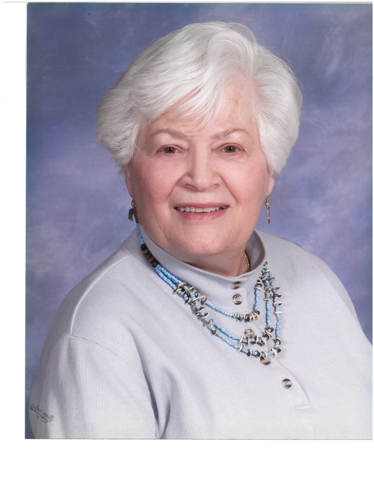 An older woman with white hair and a necklace.