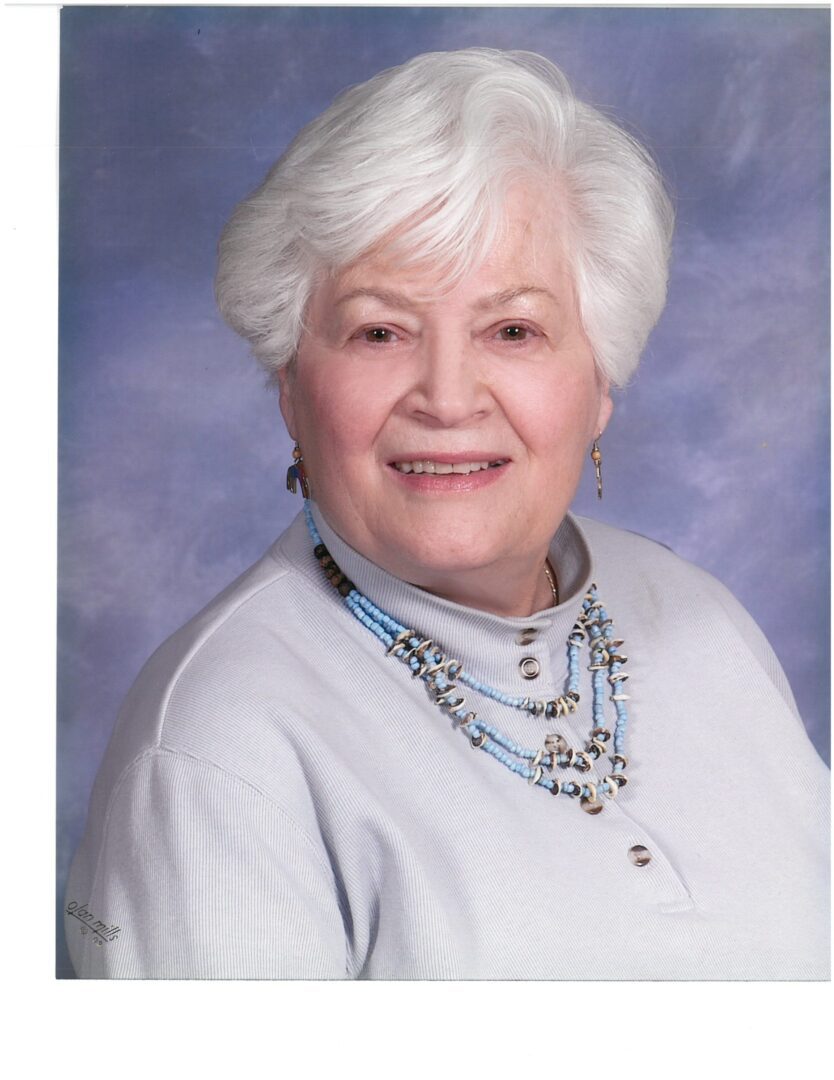 An older woman with white hair and a necklace.