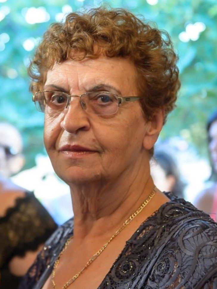 An older woman wearing glasses and a dress.
