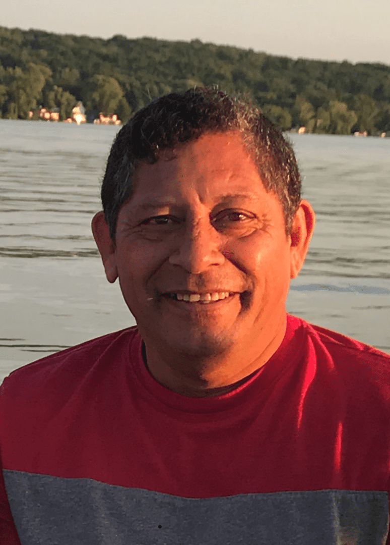 A man smiling in front of a body of water.