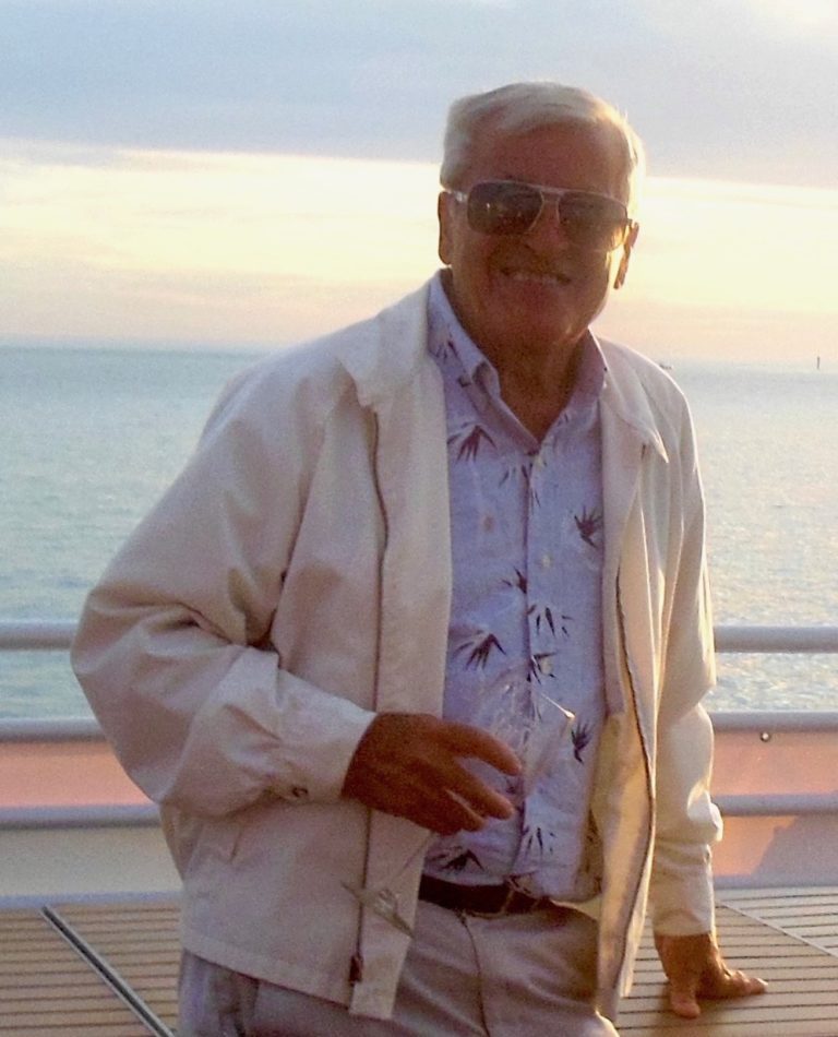 An older man standing on the deck of a cruise ship.