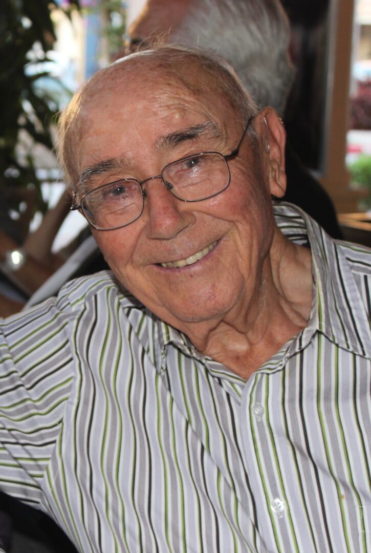 An older man wearing glasses and a striped shirt.