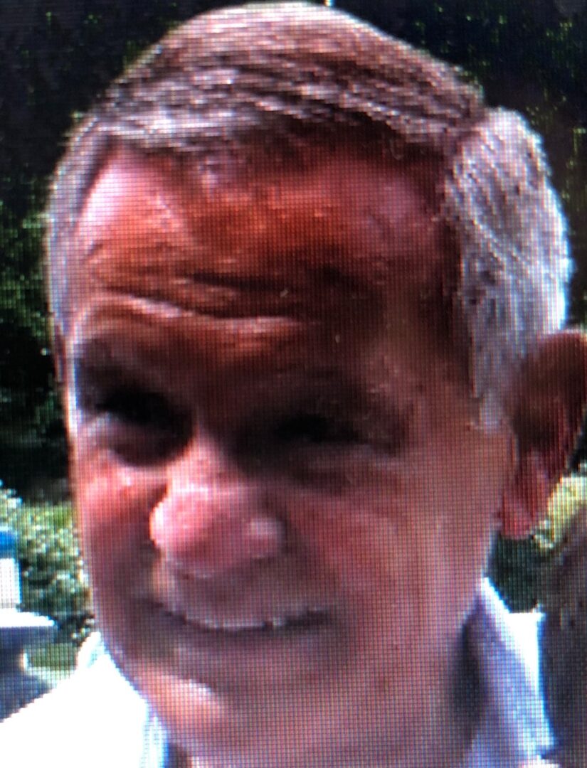 A man in a white shirt is smiling at the camera.