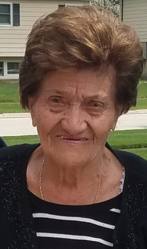 An older woman is standing in front of a house.