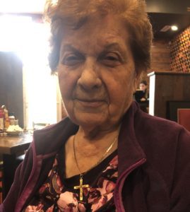 An older woman sitting at a table in a restaurant.