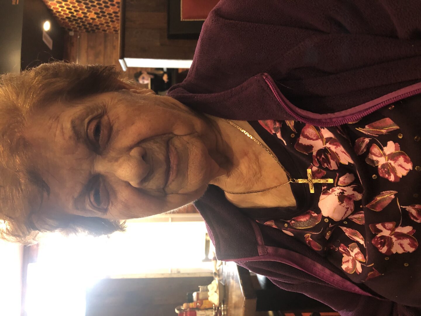 An older woman sitting at a table in a restaurant.