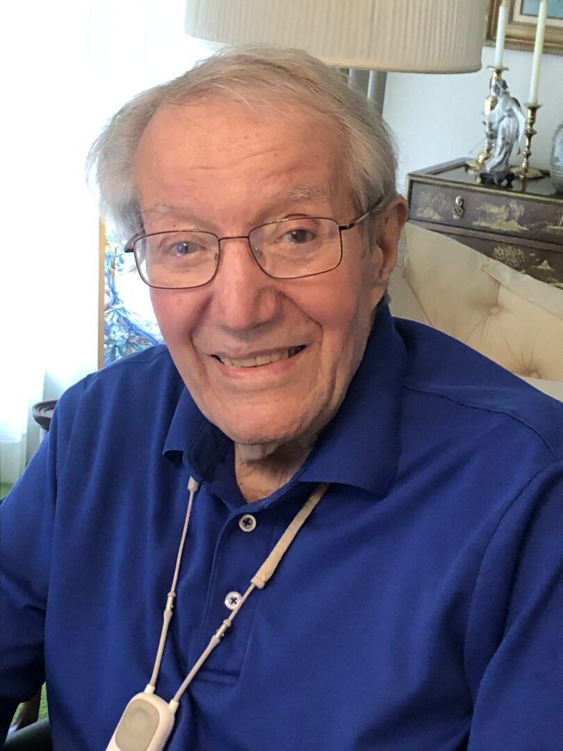 An older man in a blue shirt smiling at the camera.