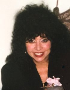 A woman with long black hair is smiling.