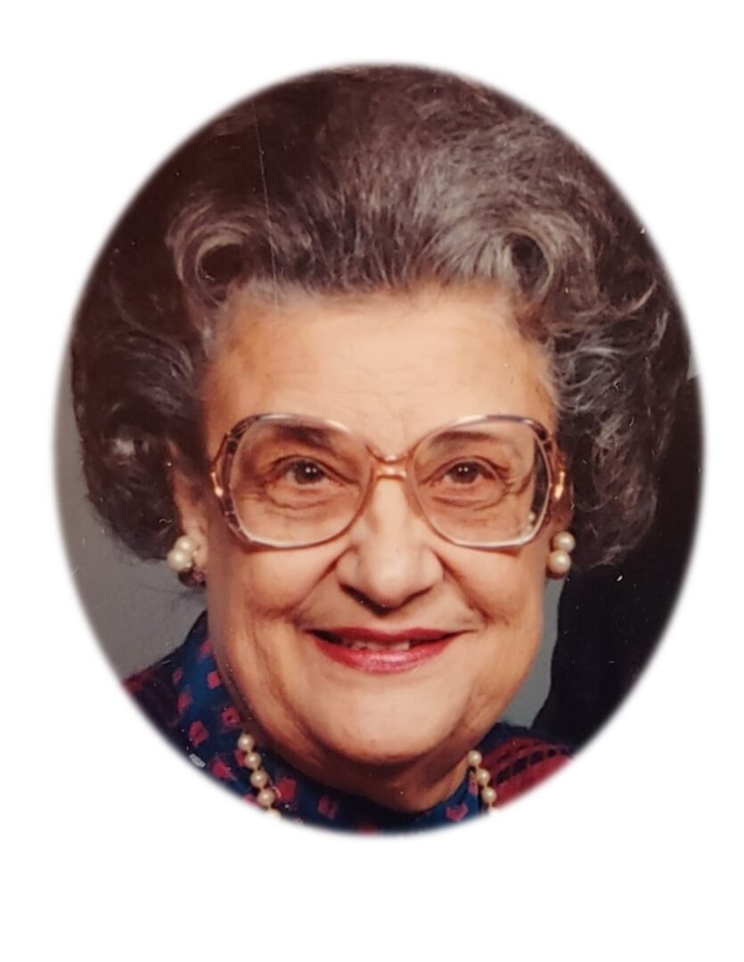 An older woman wearing glasses and a pearl necklace.