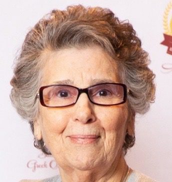 An older woman wearing glasses and a sweater.