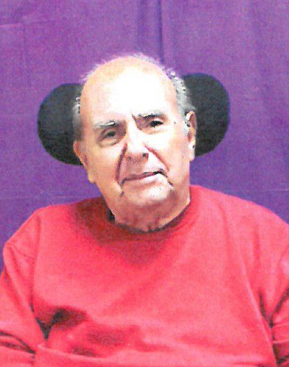 An older man in a red shirt with ear muffs.