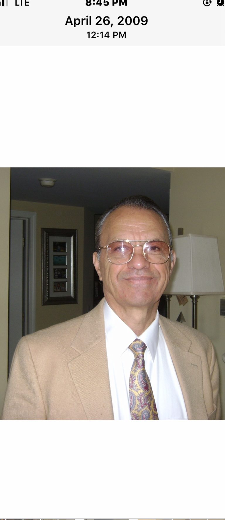 A man wearing glasses and a tan suit.