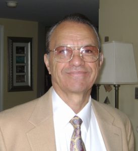 A man wearing glasses and a tan suit.