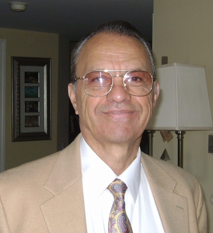 A man wearing glasses and a tan suit.