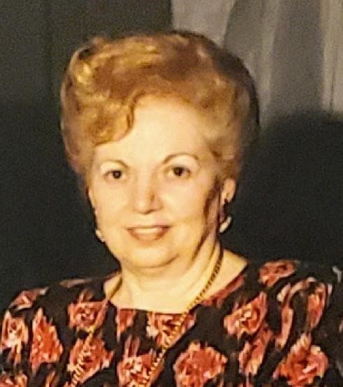A woman in a floral dress is posing for a photo.