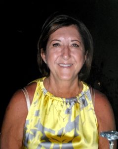 A woman in a yellow dress smiling at the camera.