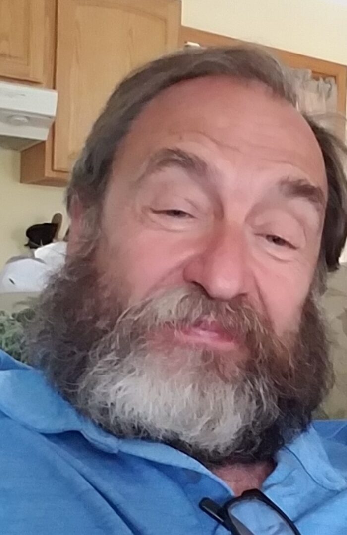 A man with a beard sitting on a couch.