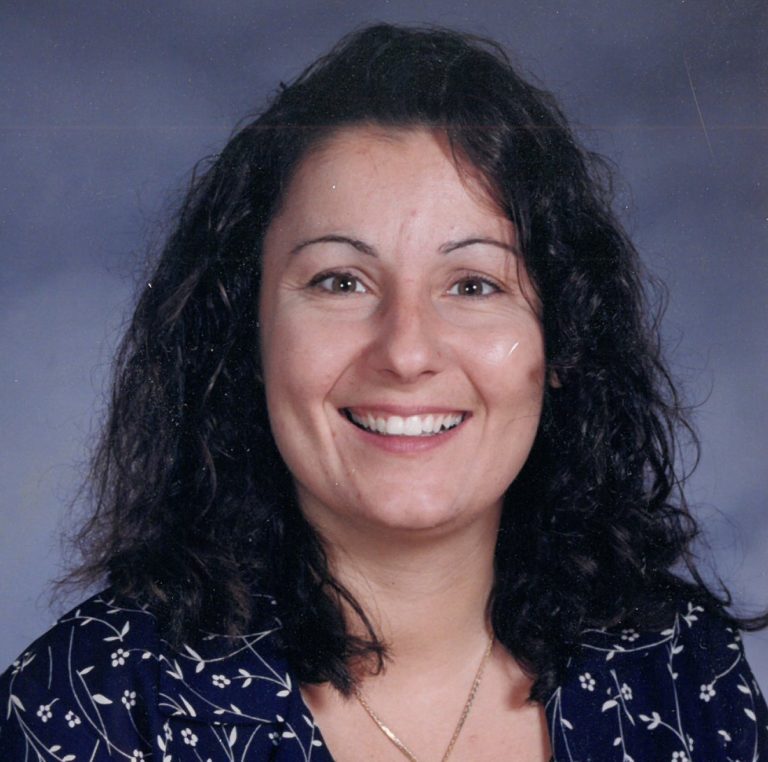A woman smiling in a blue shirt.