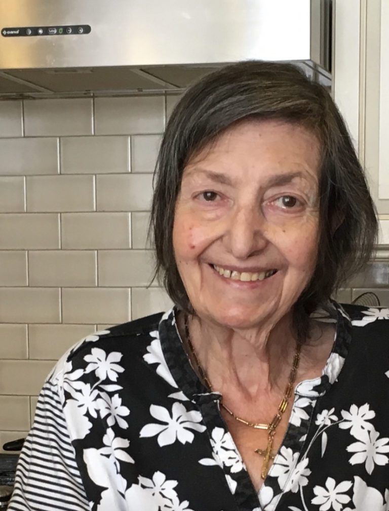 An older woman smiling in a kitchen.