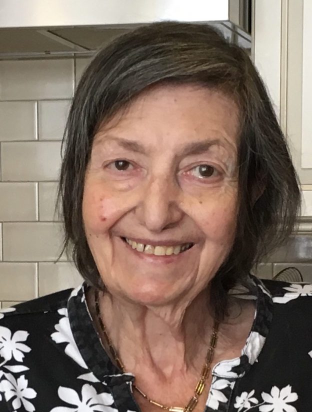 An older woman smiling in a kitchen.
