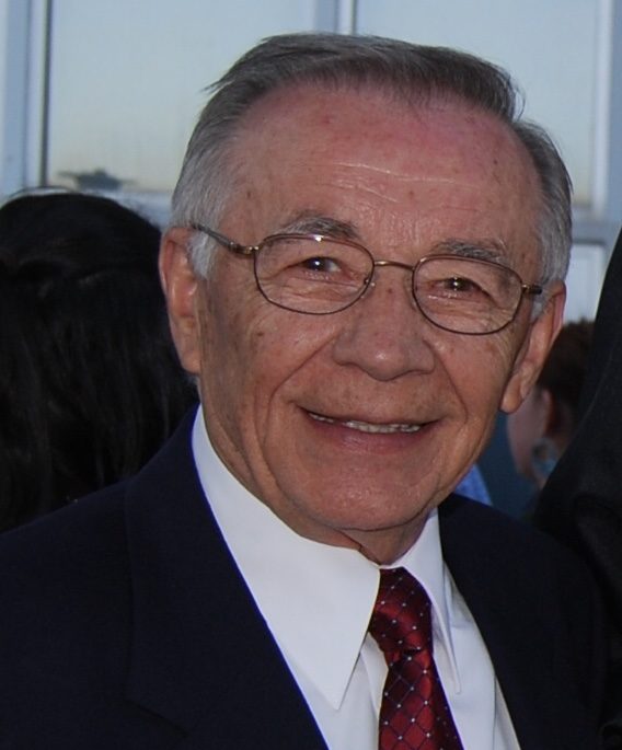 An older man in a suit and tie smiles for the camera.