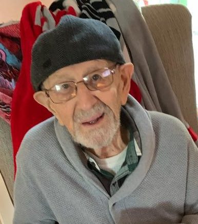 An older man sitting on a couch with a cup of coffee.