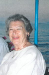 An older woman is sitting in front of a boat.
