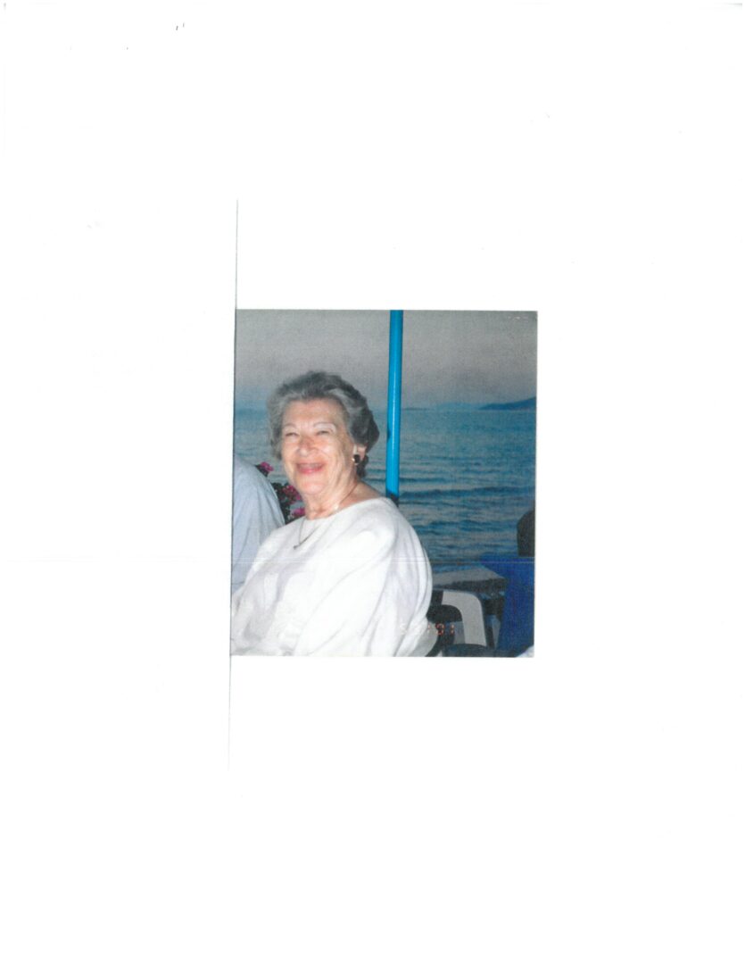 An older woman is sitting in front of a boat.
