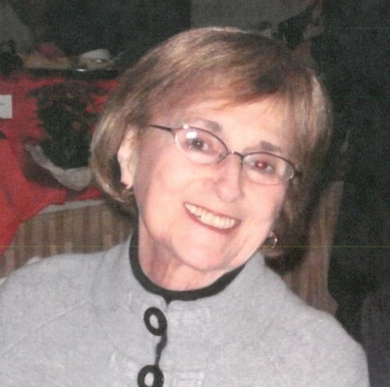 An older woman wearing glasses and a sweater.