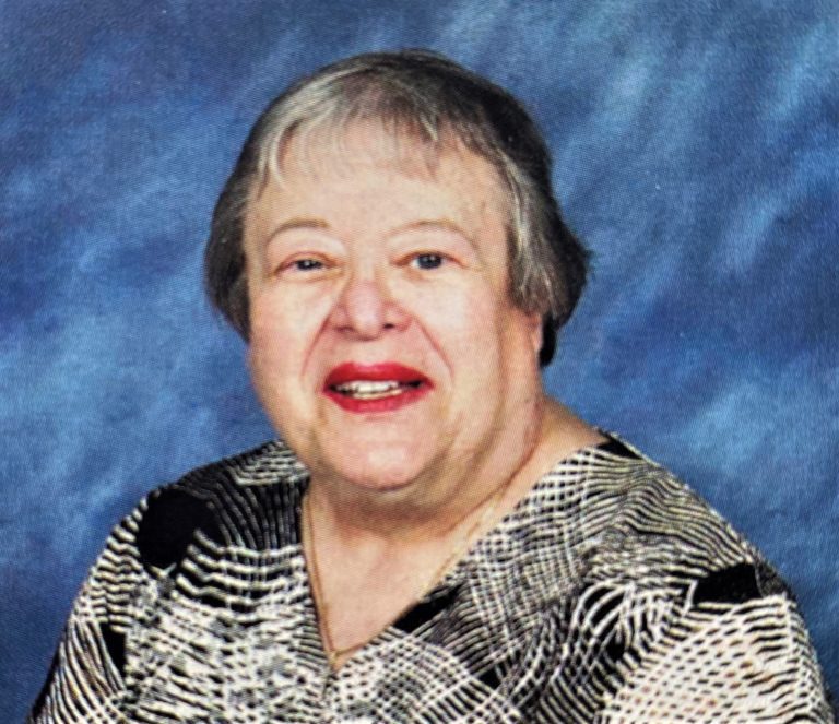 A portrait of an older woman wearing a patterned shirt.
