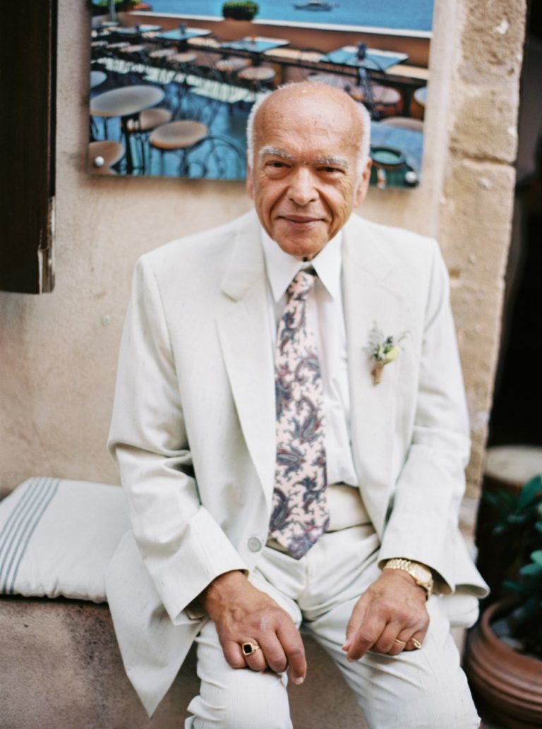 An older man in a white suit and tie.