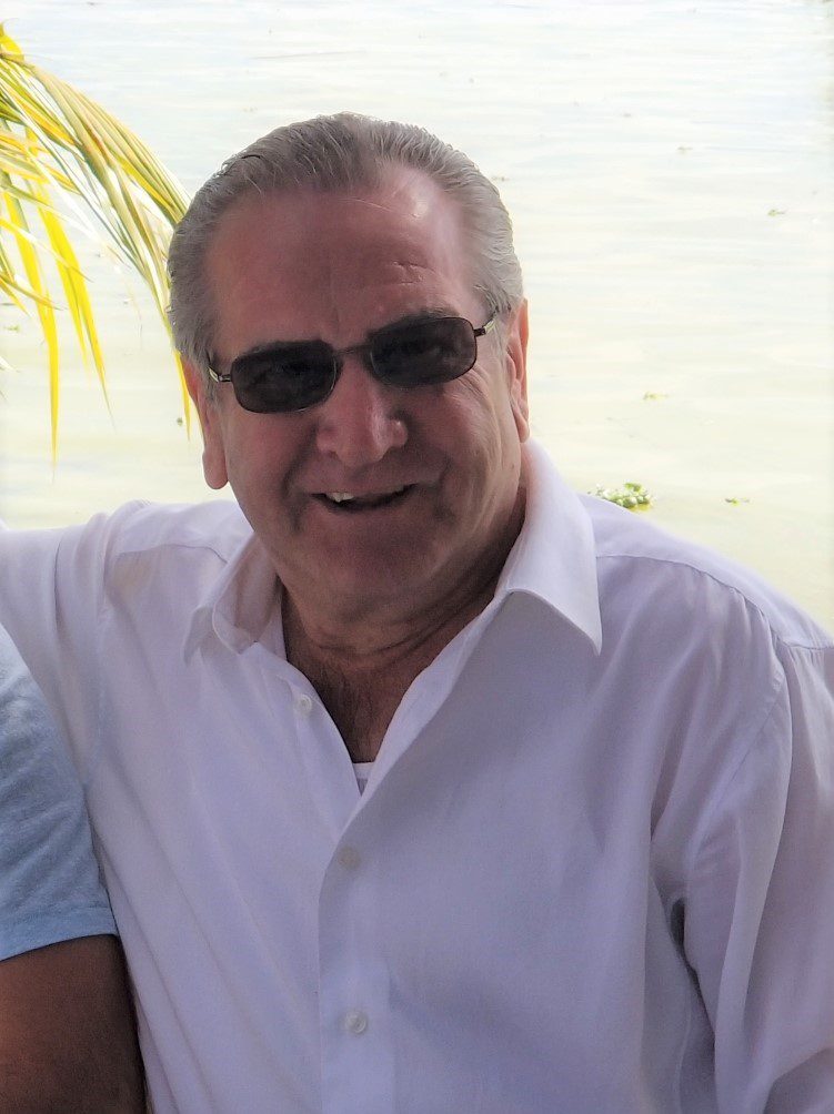 A man in a white shirt and sunglasses is posing for a photo.