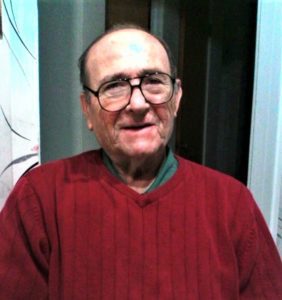 An older man wearing glasses and a red sweater.