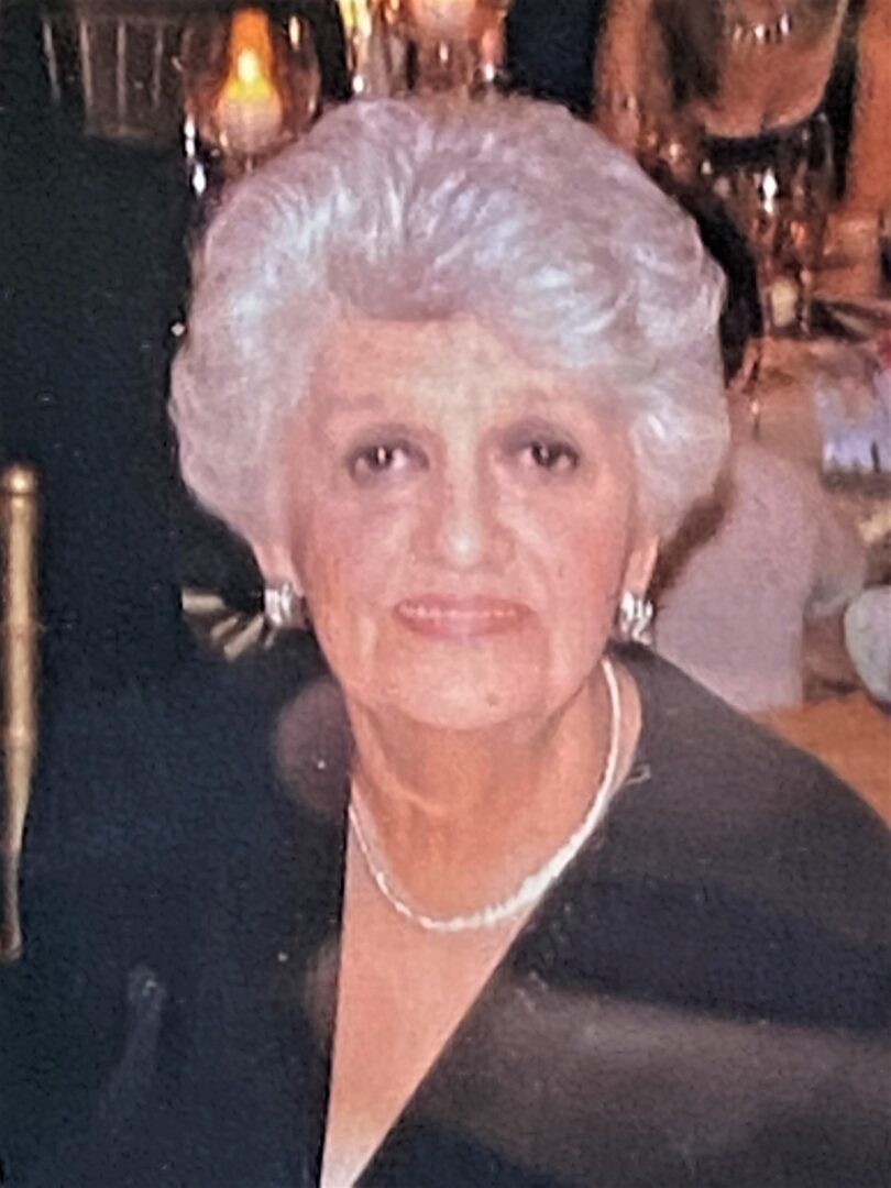 An older woman in a black dress sitting at a table.