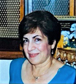 A woman in a blue dress smiling for the camera.