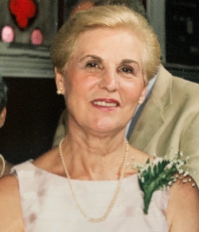 An older woman wearing a dress and pearls.